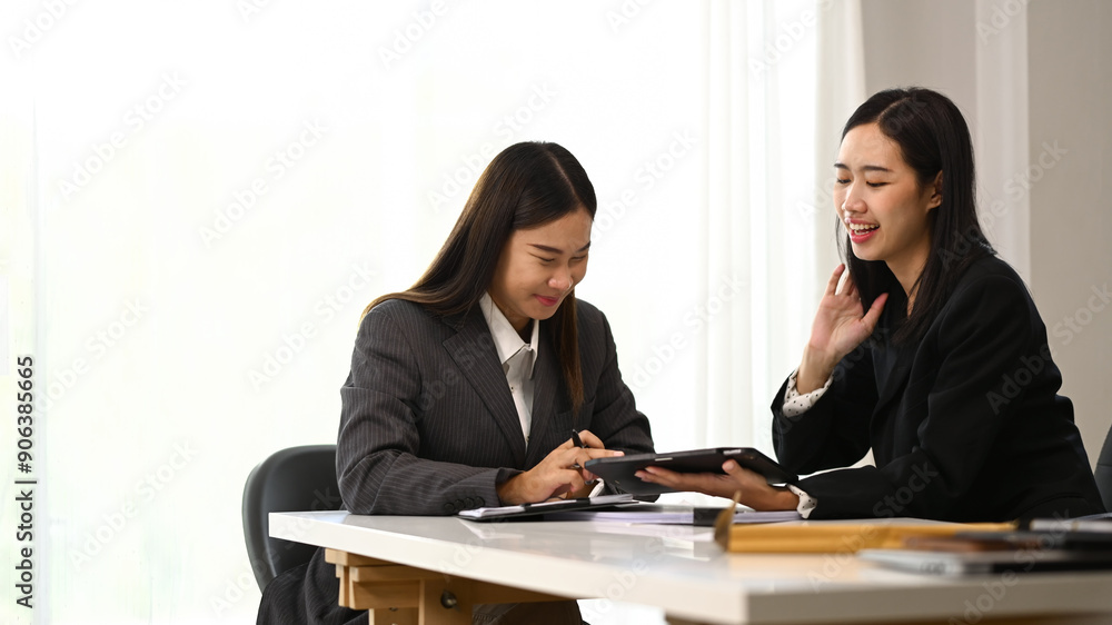 Cheerful office workers using digital tablet together and planning marketing project at co working space Cheerful office workers using digital tablet together and planning marketing project at co working space