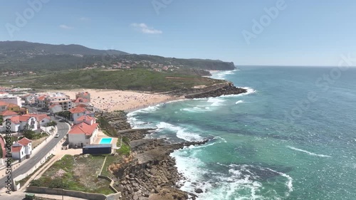 Sinta Coastline, Portugal  with rocky cliffs, crashing waves and houses perched on cliff edges. Small seaside town drone aerial view