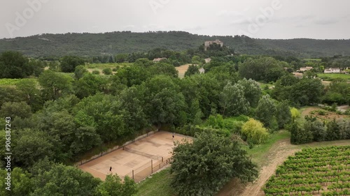 Couple play tennis on private court in South of France Vineyards, Castle and mountains in background, winelands. Aerial Drone footage