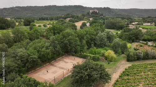 Couple play tennis on private court in South of France Vineyards, Castle and mountains in background, winelands. Aerial Drone footage