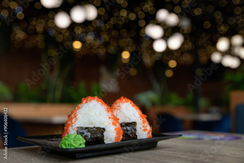 Onigiri or japanese rice balls served on the wooden tabletop in the restoran. Rice triangle with fish caviar and  seaweed. Japanese onigiri sushi. Korean Samgak-gimbap. Selective focus. photo