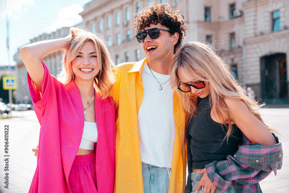 Group of young three stylish friends posing in the street. Fashion man and two cute female dressed in casual summer clothes. Smiling models having fun. Cheerful women and guy outdoors, in sunglasses Group of young three stylish friends posing in the street. Fashion man and two cute female dressed in casual summer clothes. Smiling models having fun. Cheerful women and guy outdoors, in sunglasses