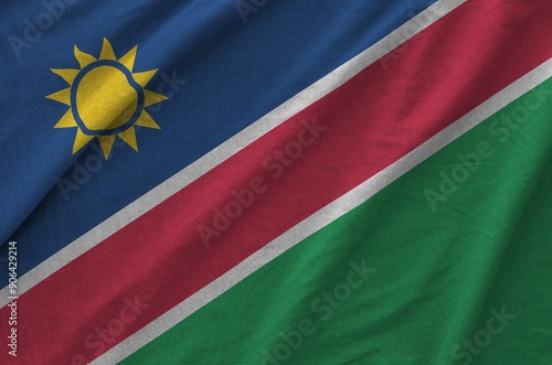 Namibia flag depicted on folded wavy fabric of old cloth close up photo