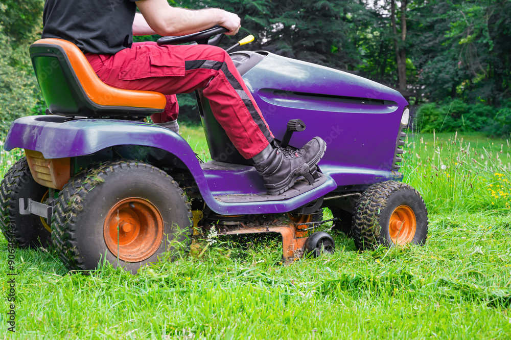 Man mowing lawn with riding lawn mower. Side view Man mowing lawn with riding lawn mower. Side view