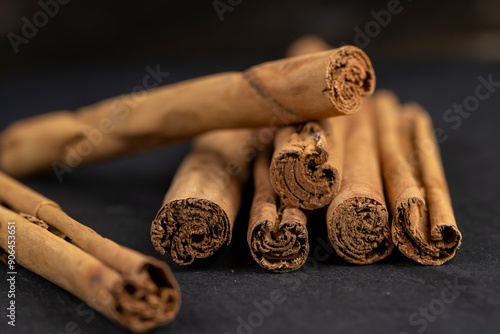 Thick wooden cinnamon on a black slate board photo