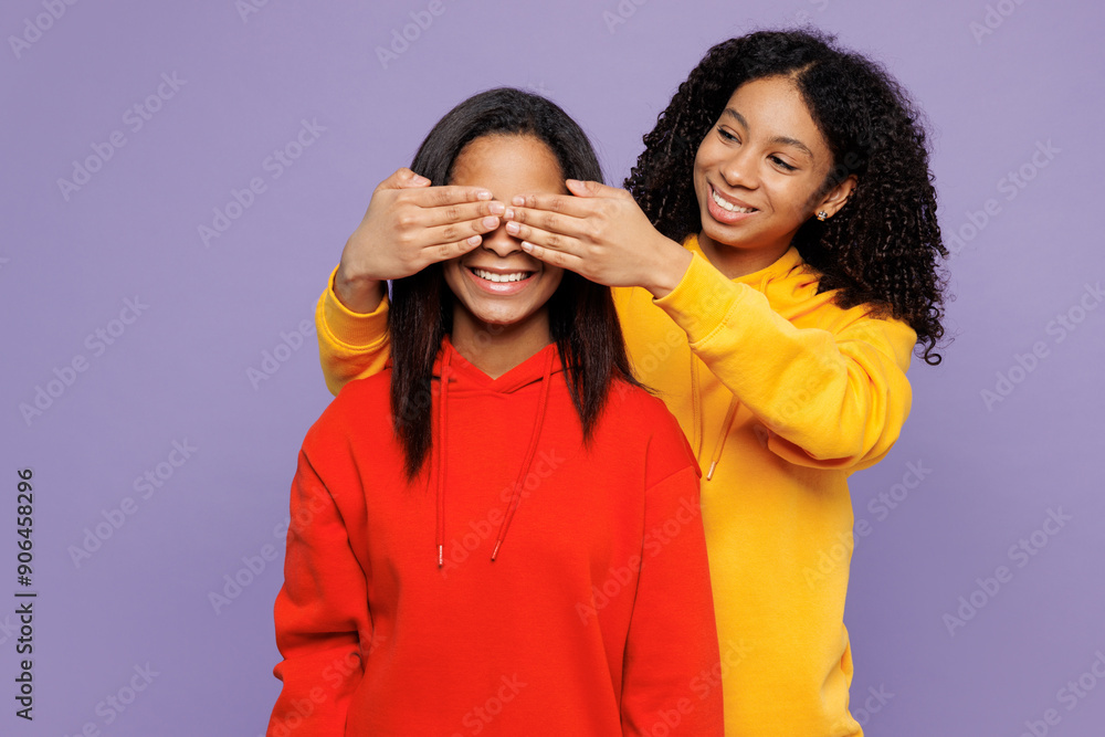 Two young little kid teen girls women they wears red yellow hoodie casual clothes close eyes with hands play guess who or hide and seek isolated on plain pastel purple background. Lifestyle concept.