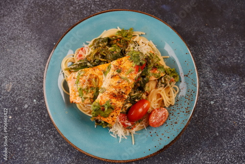 Salmon Fillet in creamy sauce with spaghetti, cream cheese and spinach and cherry tomatoes close-up on plate