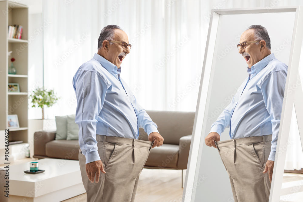 Fototapeta premium Mature man trying on a pair of pants in front of a mirror