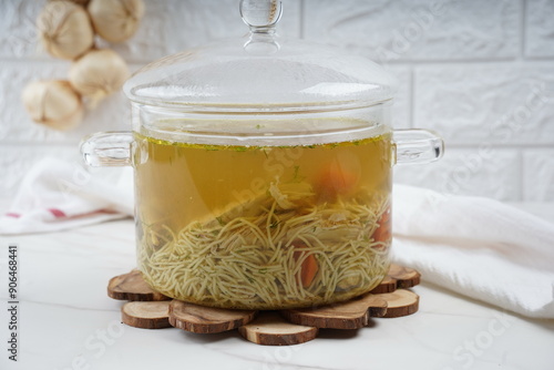 Chicken soup, chicken broth, with pieces of chicken and vegetables. Chicken bouillon in transperent glass pot