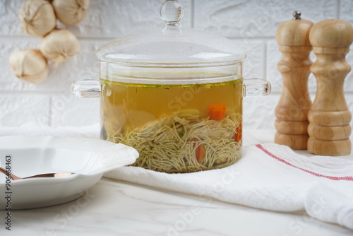 Chicken soup, chicken broth, with pieces of chicken and vegetables. Chicken bouillon in transperent glass pot
