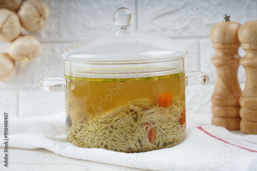 Chicken soup, chicken broth, with pieces of chicken and vegetables. Chicken bouillon in transperent glass pot