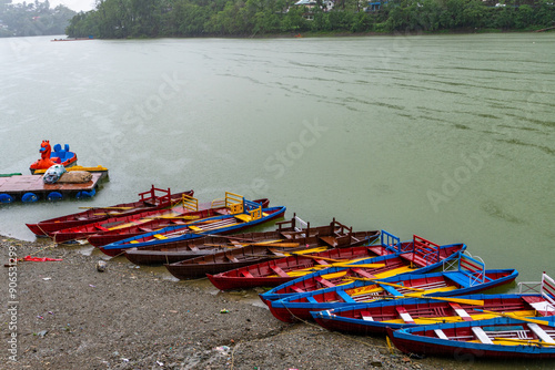 Empty boats lined up on the lakeside at Bhimtal Lake during the monsoon season, an off-season period for tourists in Almora, Uttarakhand, India. photo