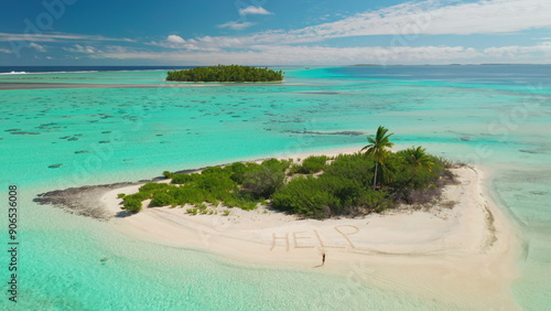 Aerial drone footage of a castaway writing help on the beach of a small desert island with palm trees, surrounded by a turquoise lagoon