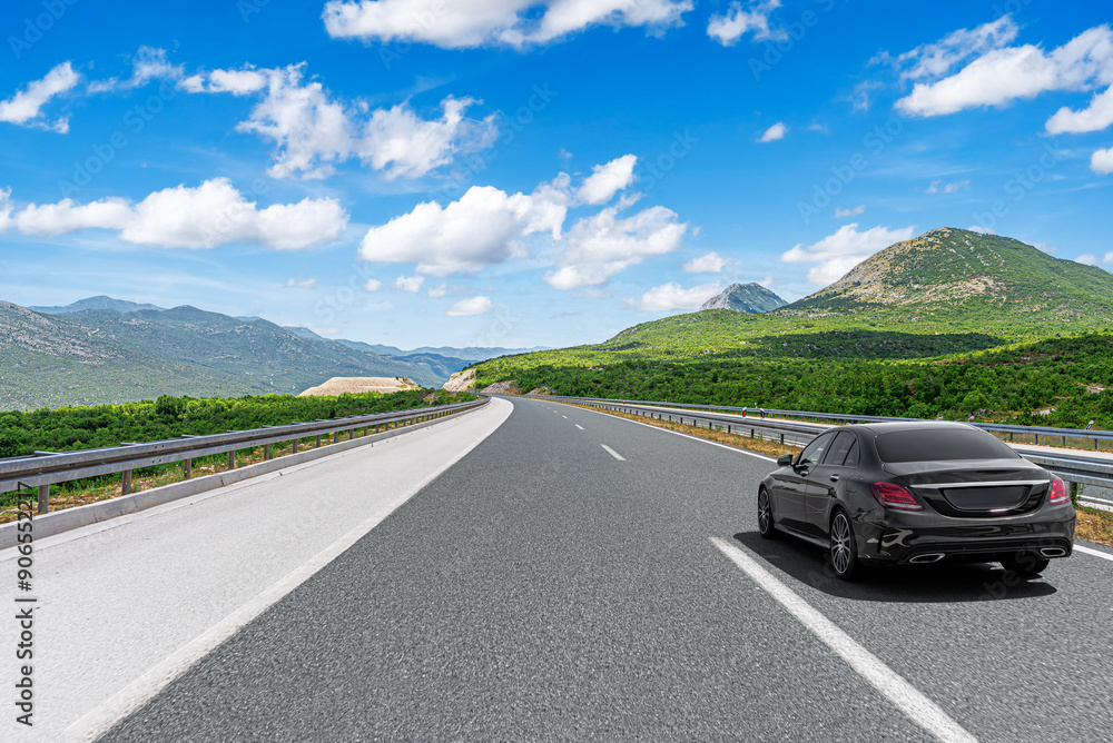 The car is driving along the highway surrounded by picturesque nature.