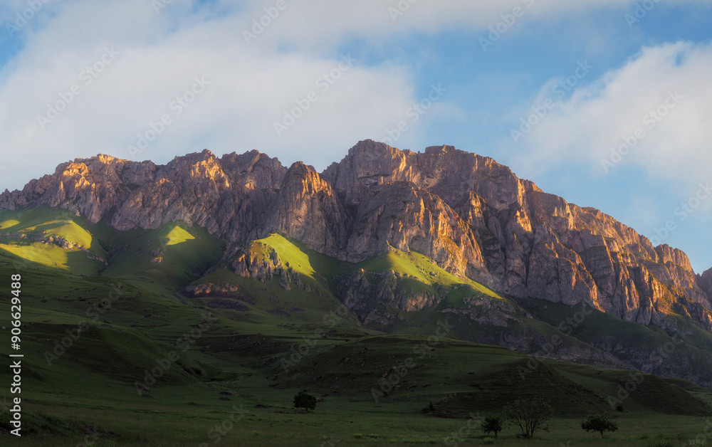 Fototapeta premium Mountain landscape with blue sky. Panoramic view of green hills. Beautiful panoramic mountain landscape under a blue sky with lush green hills and valley scenery..