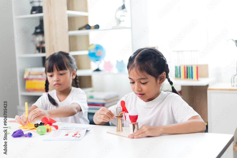 Fototapeta premium two sibling Asian girl playing windmill stacks at home