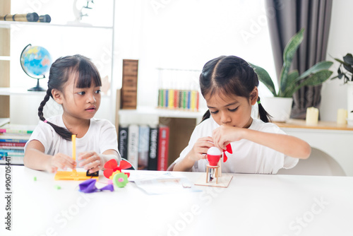 two sibling Asian girl playing windmill stacks at home