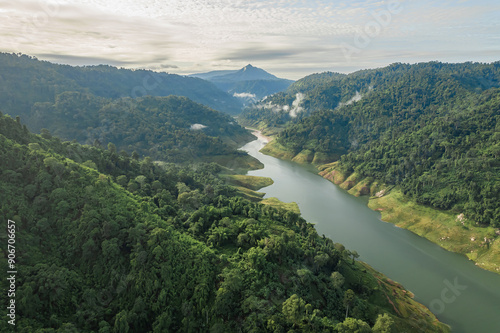 Tranquil river meanders through verdant hills under the gentle watch of a cloud-speckled sky