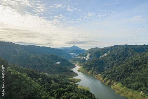 Tranquil river meanders through verdant hills under the gentle watch of a cloud-speckled sky