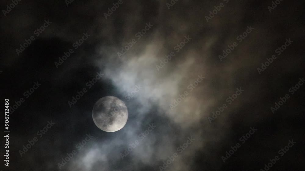 The full moon shines down on the Earth at night, with occasional clouds obscuring the light. The full moon shines down on the Earth at night, with occasional clouds obscuring the light.