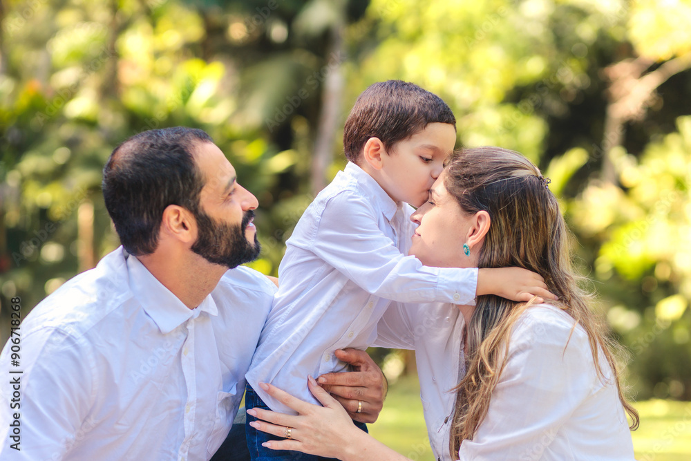 Brazilian family sharing a tender kiss outdoors. A young boy lovingly kisses his mother while the father looks on with pride and joy. Perfect for themes of love, family, and heartfelt moments Brazilian family sharing a tender kiss outdoors. A young boy lovingly kisses his mother while the father looks on with pride and joy. Perfect for themes of love, family, and heartfelt moments