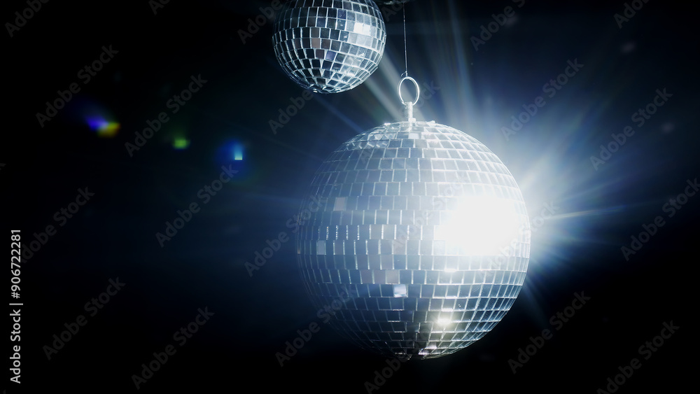 Obraz premium Close-up of a spinning disco ball reflecting dynamic rays of light against a black background. Perfect for creating a vibrant and energetic atmosphere at parties and events.