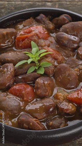 Ful Mudammas (Medammes) in bowl. Egyptian dish made of dried fava bean, onion, garlic, tomatoes, and olive oil, often served as a sandwich filler. Wooden rustic table. Vertical video. photo