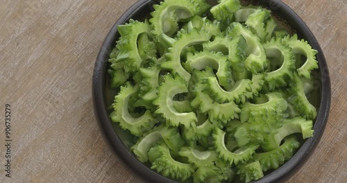 Deseeded and sliced raw bitter melon (Momordica charantia) on a plate. Copy space. Table spin.  photo