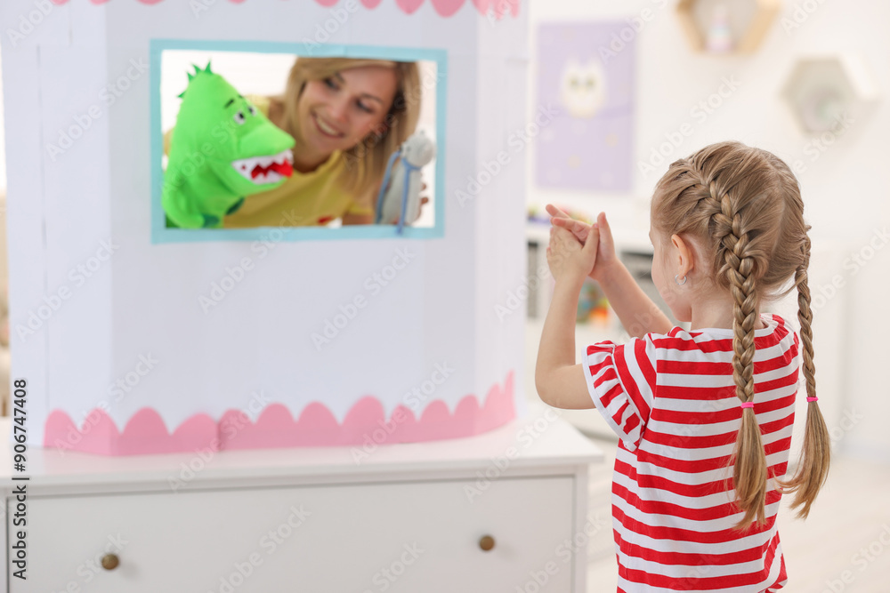 Puppet theatre. Smiling mother performing show with toys to her daughter at home, selective focus Puppet theatre. Smiling mother performing show with toys to her daughter at home, selective focus