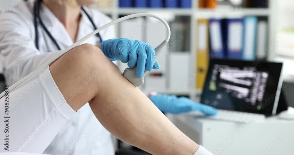 Doctor uses sonography to take sports x-ray of patient knee. Details of anatomy of leg of orthopedist during ultrasound diagnostics in a medical office. Doctor uses sonography to take sports x-ray of patient knee. Details of anatomy of leg of orthopedist during ultrasound diagnostics in a medical office.