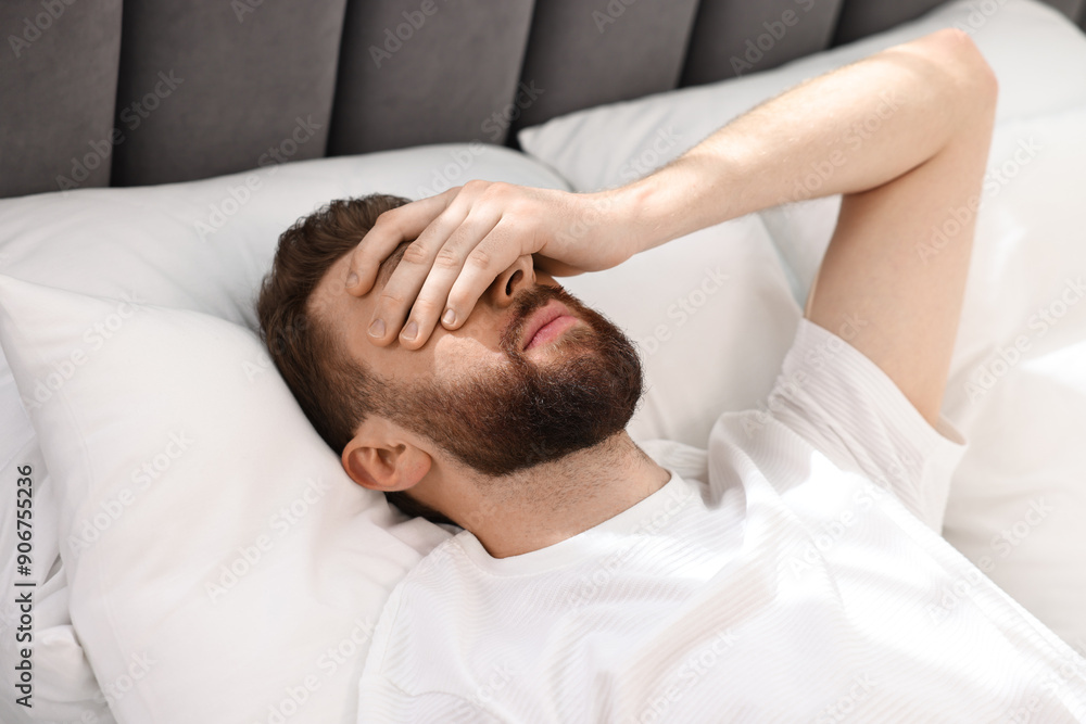 Handsome young man waking up in bed at morning