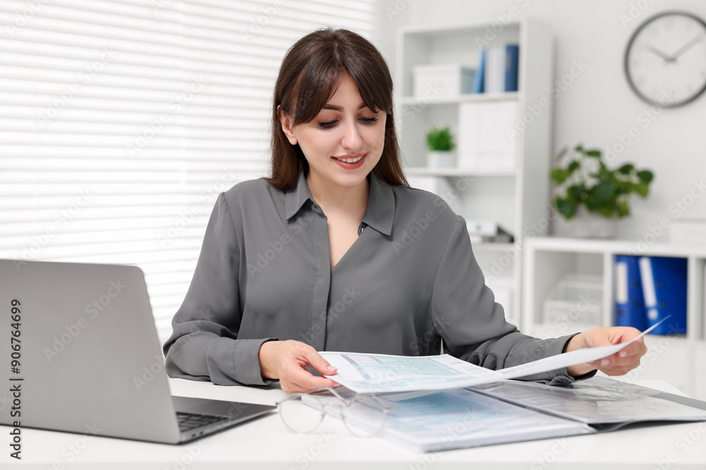Smiling secretary doing paperwork at table in office Smiling secretary doing paperwork at table in office