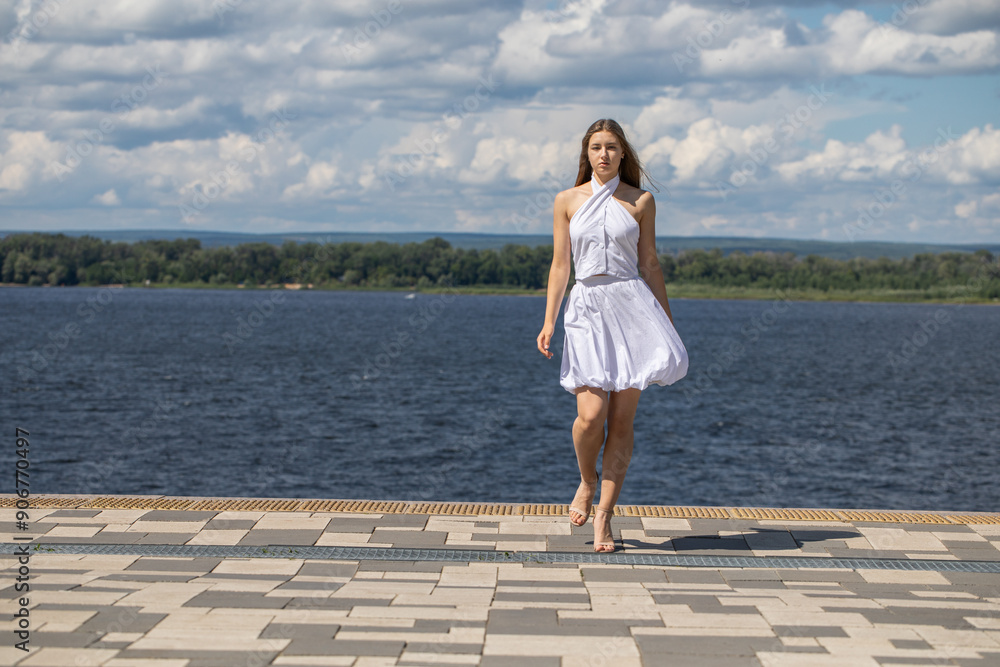 Young beautiful woman in a summer dress walking along the embankment Young beautiful woman in a summer dress walking along the embankment