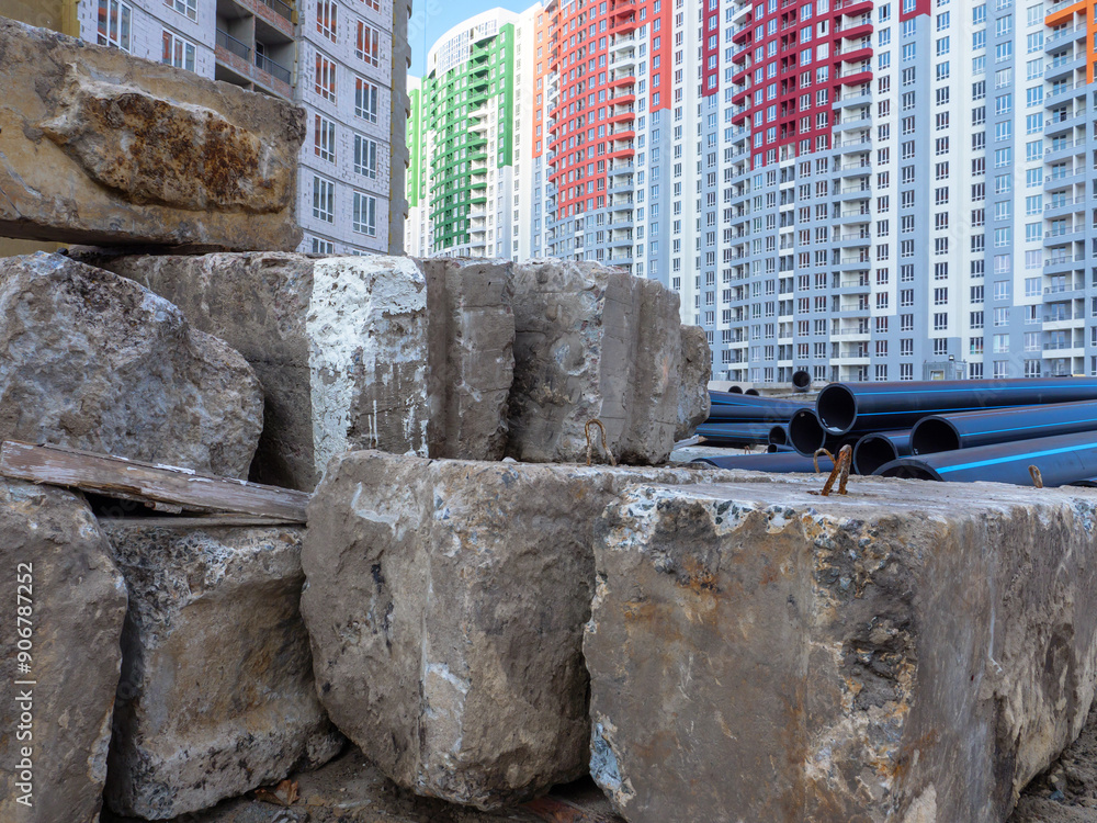 A building site with huge concrete blocks and big black pipes in the foreground and new colorful high-rise buildings in the background in Kyiv, Ukraine. New district under construction concept.