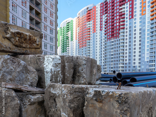 Obraz na płótnie A building site with huge concrete blocks and big black pipes in the foreground and new colorful high-rise buildings in the background in Kyiv, Ukraine. New district under construction concept. w salonie