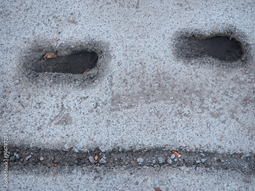 Obraz na płótnie Deep footsteps and bike tire print embedded in wet cement and filled with water after the rain, and autumn leaf floating in it. w salonie