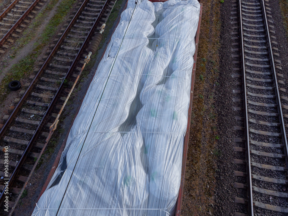 Top view over a freight train wagon without a roof loaded with huge white sacks and waiting at the station in Kyiv city, Ukraine.