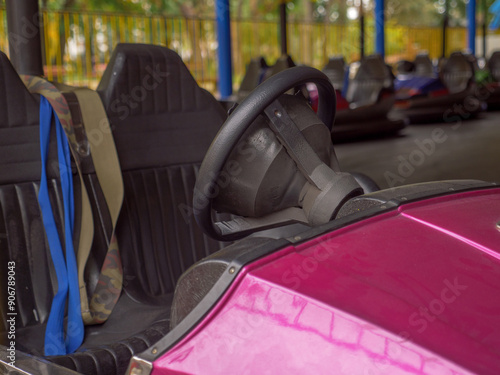 Obraz na płótnie Closeup of a wheel and two seats of an electric old-fashioned bumper car and a row of autos standing behind in a city amusement park. Traditional family entertainment and active leisure time outdoors. w salonie
