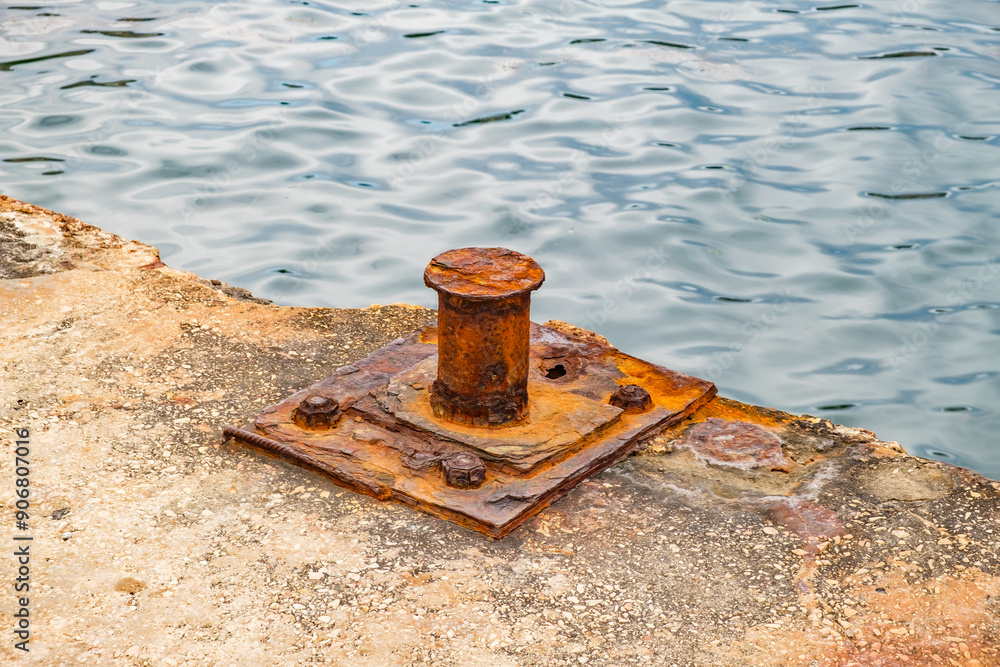 rusty old bollard on concrete pier, close-up rusty old bollard on concrete pier, close-up