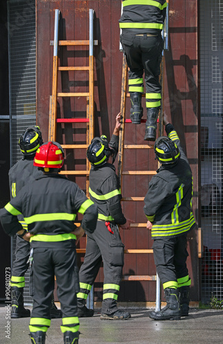 Fireman Fire chief coordinates firefighters assembling  rung leaning ladder to climb building photo