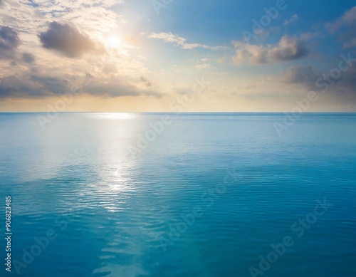 Closeup surface of calm ocean blue sea water with sunshine and clouds behind. Abstract Background Texture.