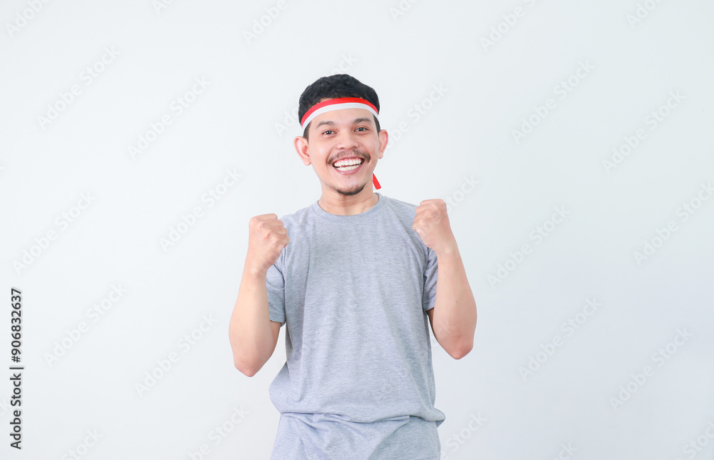 Fototapeta premium Excited young Asian man clenched fist showing excitement during celebrating indonesian independence day on 17 august isolated on white background