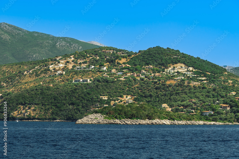 Sea view of low rise houses on the hill and close to the beach surrounded by green forest, Lefkada, Ionian Island, Greek Islands, Greece, Europe Sea view of low rise houses on the hill and close to the beach surrounded by green forest, Lefkada, Ionian Island, Greek Islands, Greece, Europe