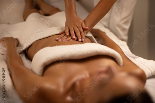 Canvastavla Masseur making relaxing massage of stomach for lying woman in calm spa center interior