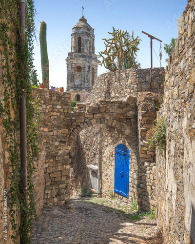 Fototapeta Naklejka Na Ścianę i Meble -  Blue door and bell tower view in a street of the ghost town Bussana Vecchia. Liguria, Italy
