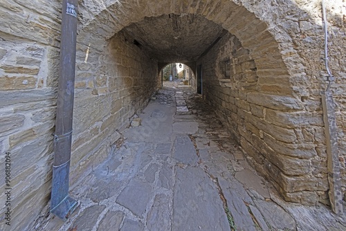 a stone walkway going between buildings with windows on either side