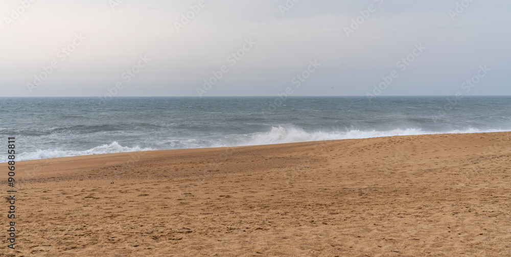 Overlooking a quiet beach with golden sands that meet rolling waves under a somber sky. Powerful waves cresting towards the sandy shore offering a sense of calm and solitude. Overlooking a quiet beach with golden sands that meet rolling waves under a somber sky. Powerful waves cresting towards the sandy shore offering a sense of calm and solitude.