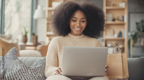 Happy African American Woman Online Shopping - Sitting on Sofa in Living Room with Laptop on Her Lap, Buying or Purchasing on the Internet from Home Photo