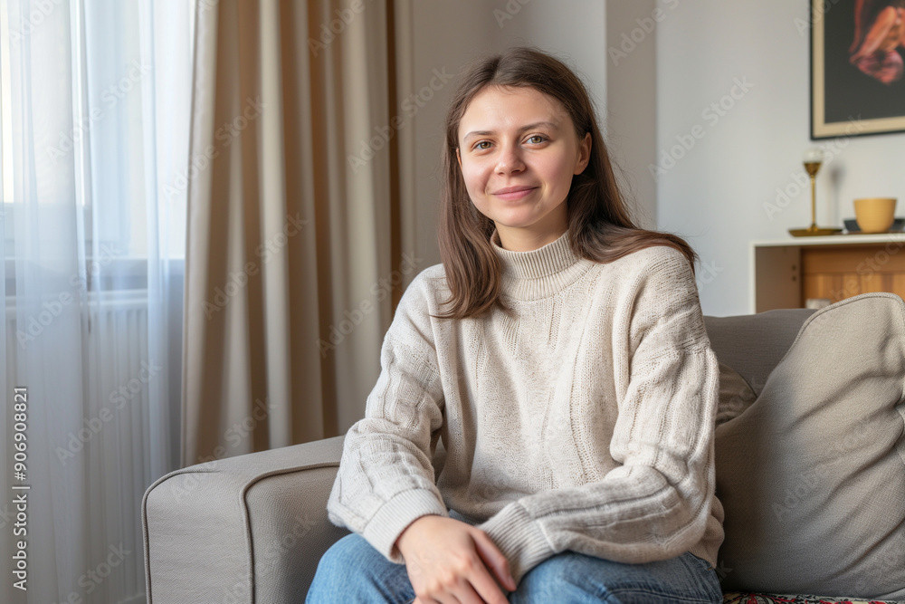 Young adult woman sitting on sofa smiling at home Young adult woman sitting on sofa smiling at home