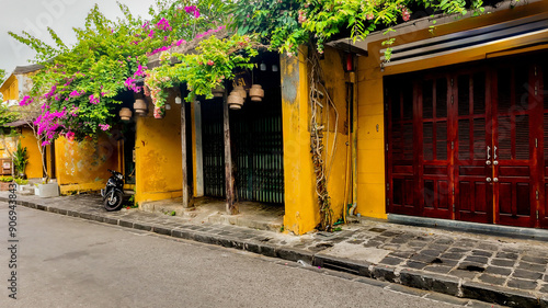 Quaint street in Hoi An, Vietnam, showcasing yellow-walled buildings draped in vibrant bougainvillea, perfect for Tet holiday-themed imagery photo